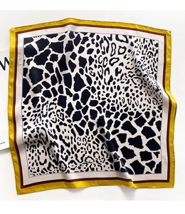 Detailed close-up of leopard and giraffe print silk scarf with stylish yellow contrast borders