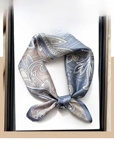 Détail d'un foulard en soie à motif paisley élégant dans les tons gris-bleu et beige