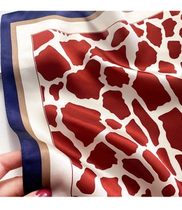Detail of red giraffe print silk scarf with navy blue and gold satin borders