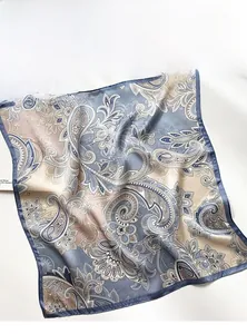 Détail d'un foulard en soie montrant le motif paisley gris bleu et le tissu doux