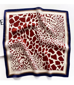 Macro detail of leopard print silk scarf with deep red and geometric animal patterns
