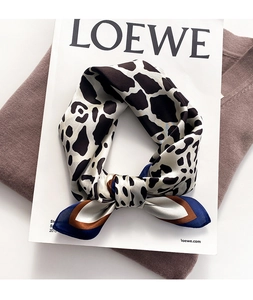 Close-up of leopard print silk scarf with contrast border and smooth satin texture