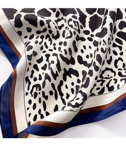 Close-up of leopard print silk scarf with contrast blue and brown borders and satin sheen