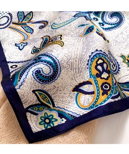 Detailed close-up of paisley silk scarf with rolled hem edges and fine texture