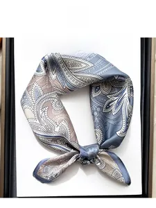 Détail d'un foulard en soie à motif cachemire bleu posé sur un magazine de mode