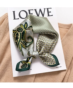 Close-up of silk square scarf with paisley patterns on a camel knitted sweater