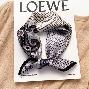 Elegant silk scarf with paisley and geometric patterns folded on a stylish magazine
