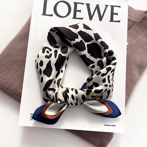 Elegant giraffe animal print silk scarf with colorful striped border on magazine background