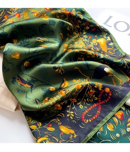 Close-up of elegant forest green silk scarf with vibrant floral and berry patterns