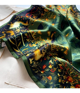 Close-up of a dark green floral silk scarf showing satin texture and fine rolled edges