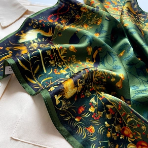 Deep green silk scarf with nature bird and berry prints on a white shirt background