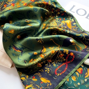 Deep green silk scarf with birds and floral print shown in elegant folded texture