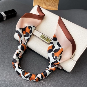 Leopard print silk scarf tied on white leather handbag handle with gold clasp detail