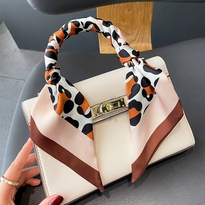 Detail of leopard print silk scarf wrapped on cream leather handbag with gold lock