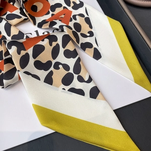 Macro detail of leopard print skinny scarf featuring orange letters and green borders