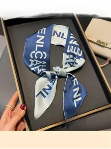 Detailed view of dark blue and beige letter print skinny scarf tied as a bow on a tray