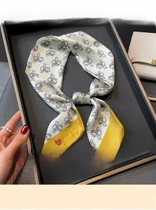 Detail of bunny print silk scarf tied as bag accessory with yellow trim and heart accents