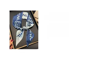 Detail view of blue and white silk scarf with digital printed letters on a dark tray