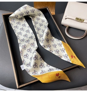 Detail of elegant cream twilly scarf with floral heart patterns on a premium leather bag