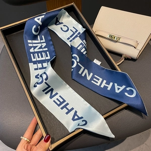 Detail of a navy and light blue letter printed silk scarf tied on a stylish handbag