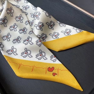 Detail of floral pattern twilly scarf with red heart accents on yellow diagonal tips