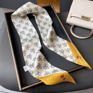 Detail of iris floral twilly scarf with yellow heart pattern ends on a tray