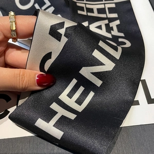 Detailed view of luxury silk scarf with letter pattern and premium serpent ring texture