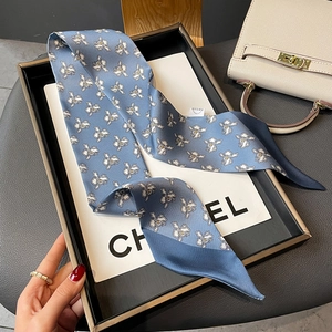 Detail of silk skinny scarf showing elegant white iris floral patterns on navy blue fabric