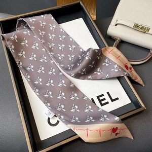Macro detail of silk-feel scarf with floral heart pattern on white display tray