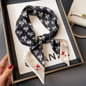 Elegant black and white floral silk scarf with red heart design tied in a bow