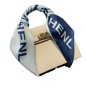Minimalist beige pebble leather handbag with blue printed silk scarf on gold clasp handle