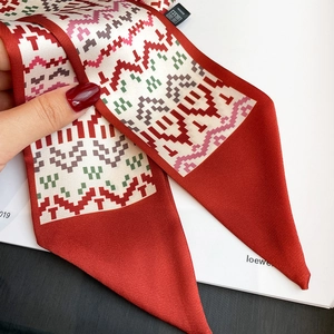 Detail of red satin narrow scarf with pixelated geometric patterns and design label