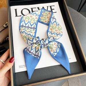 Narrow silk scarf with geometric pixel pattern in blue and orange tied in a bow