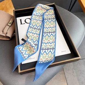 Detailed view of a geometric tribal pattern twilly scarf with bright royal blue edges