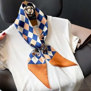 Twilly en soie élégant avec motif losange et papillon porté sur un pull en maille blanc