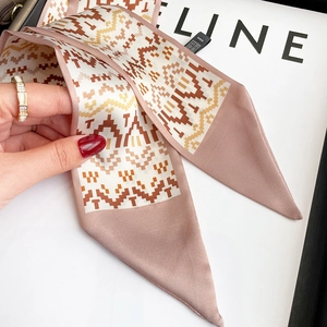 Detail of pink silk twilly scarf with geometric waves paired with a gold ring