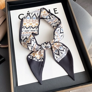Detail of bohemian geometric pattern twilly scarf tied in a bow on a white display card
