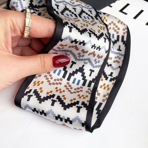 Detail showing pixelated geometric pattern twilly scarf with silky texture and gold ring