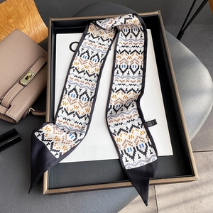 Macro shot of silk scarf with geometric pixel pattern and pointed black ends on box