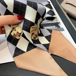 Détail d'un foulard en soie avec motif en losange noir et blanc et imprimé papillon doré