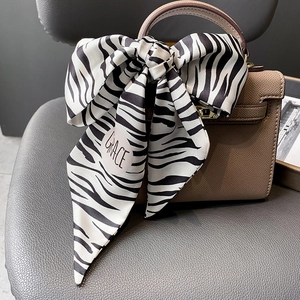 Foulard en soie à motif zèbre avec texte GRACE noué en nœud sur un sac à main brun