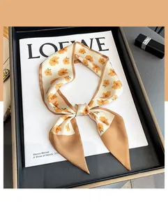 Floral silk skinny scarf on a designer book with dark leather tray and lipstick