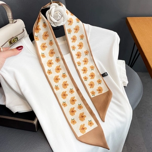 Detail of floral narrow silk scarf layered over a white knit top for styling