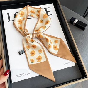 Detail of floral narrow silk scarf with elegant ochre flowers and premium silk texture