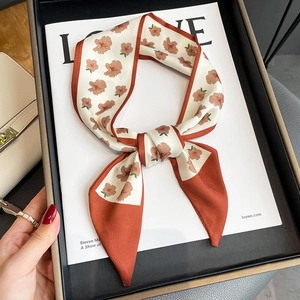 Floral skinny silk scarf with brick red border elegantly draped on a vintage book