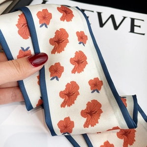 Close-up of cream floral twilly scarf with orange flowers and dark blue hem detail
