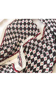 Gros plan d'un foulard en soie plissé avec des carreaux noirs et blancs et cœurs rouges