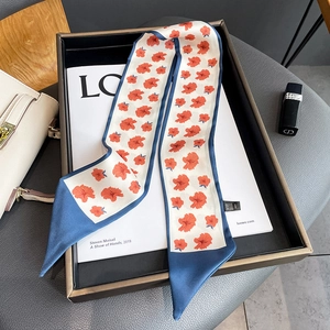 Detailed view of floral silk neckerchief on a magazine with a beige handbag