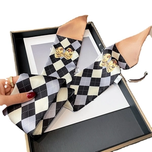 Foulard étroit en soie avec motif de losanges noirs et blancs et nœuds dorés