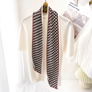 Détail d'un foulard en soie à carreaux avec cœurs rouges sur un haut en maille